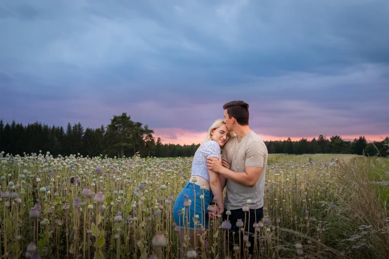 Ein Paar umarmt sich bei Sonnenuntergang in einem Feld voller Wildblumen.
